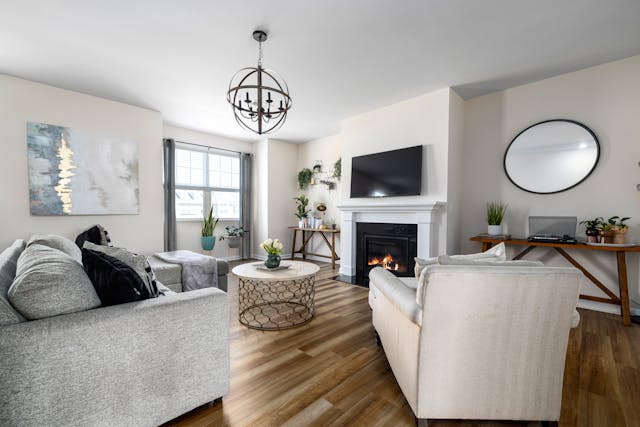 a living room with a fireplace, white walls and grey furniture